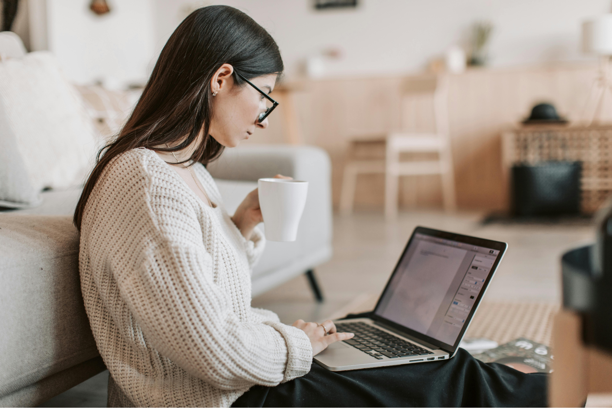 A women is using her laptop while drinking coffee