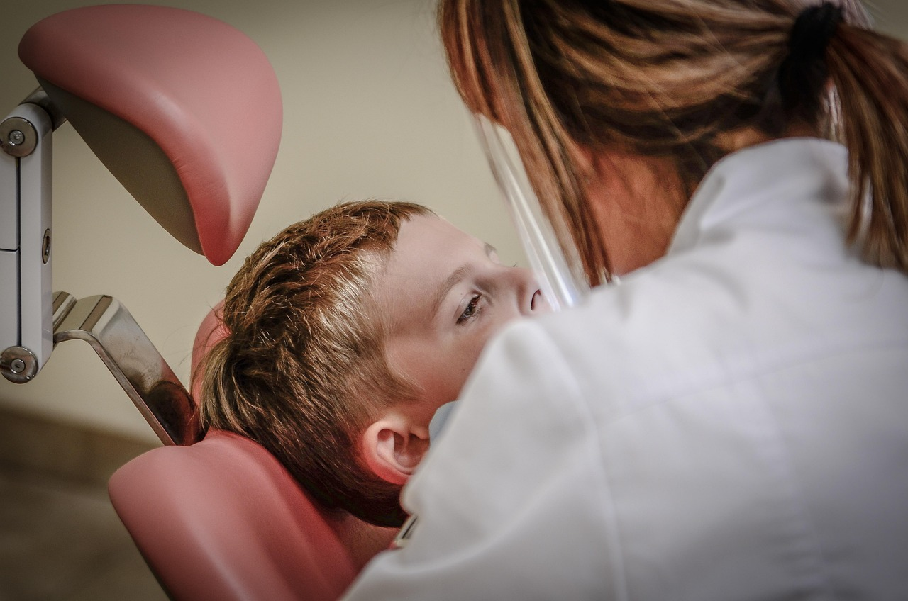A female dentist is examining at a boy