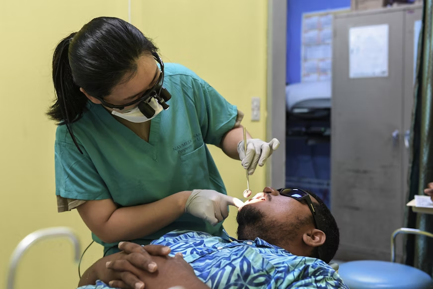 A female dentist is examining a male patient