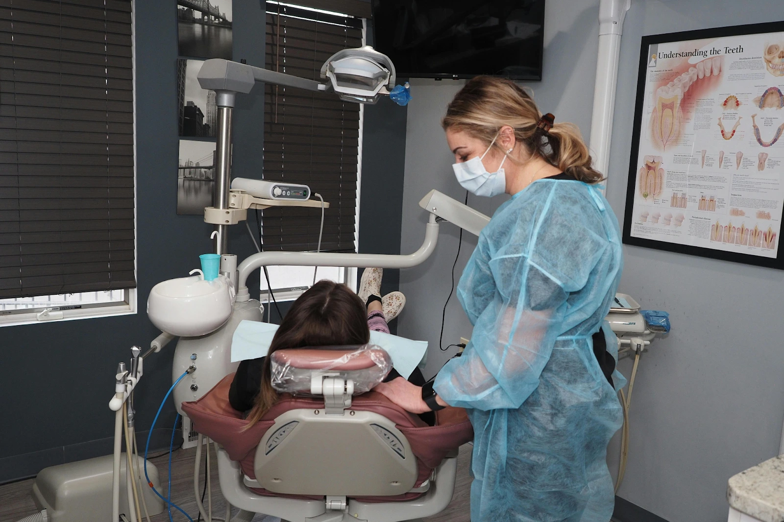 A dental hygienist prepares to treat a patient lying in a dental chair