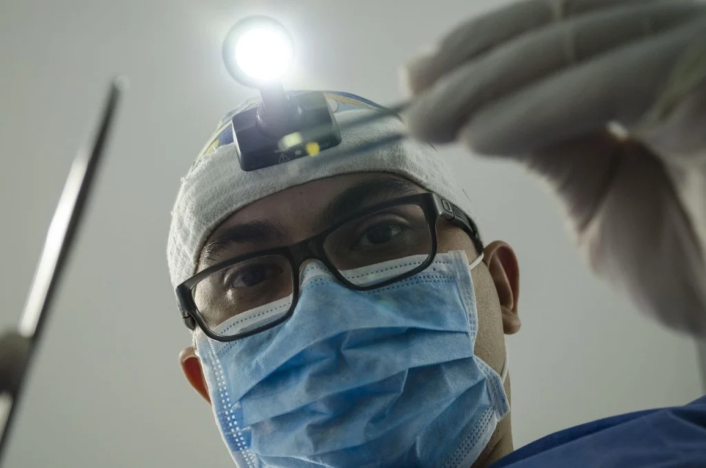 Dentist wearing glasses, a surgical mask, and a headlamp