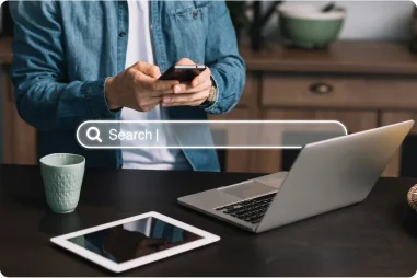 Person searching on smartphone beside laptop and tablet